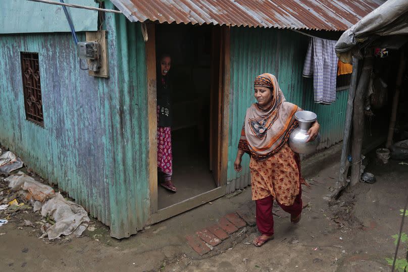 A woman walks back after collecting drinking water from a tubewell on the outskirts of Dhaka, 2016.