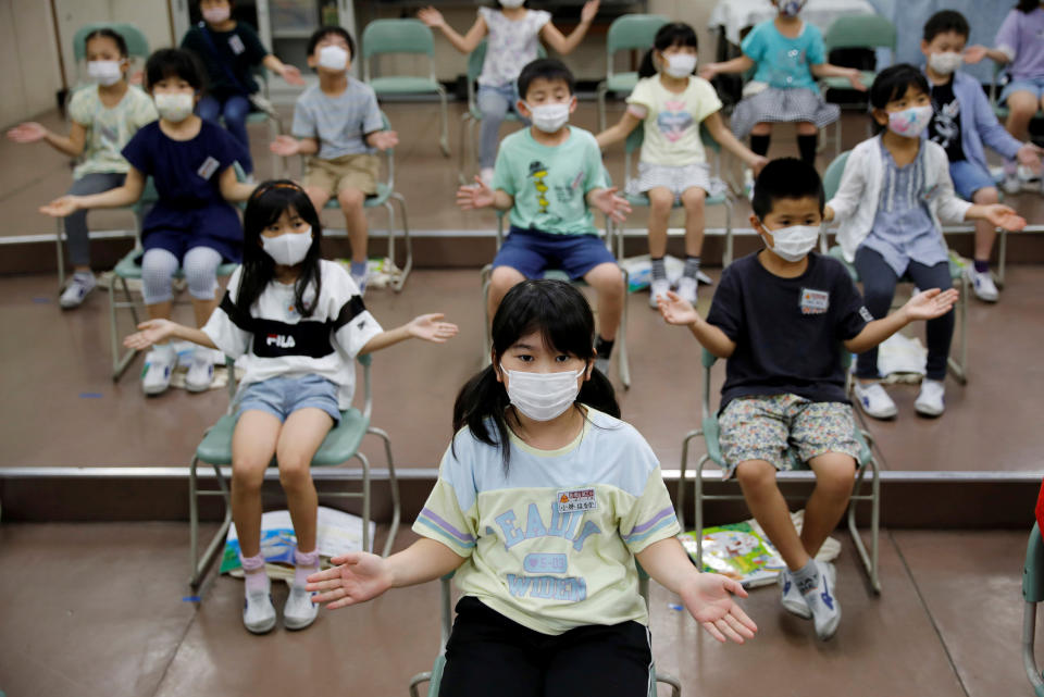 Students wearing protective face masks amid the coronavirus pandemic clap along instead of singing in a music class at Takanedai Daisan elementary school, which practices various methods of social distancing in order to prevent the infection, in Funabashi, east of Tokyo.