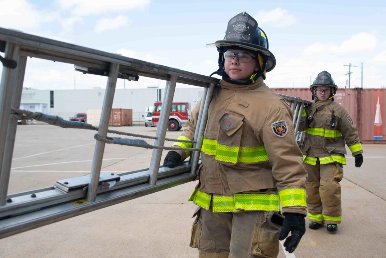 Topeka Fire Department recruits BreAnna Droge, left, and Alyssa Conway carry a ladder to practice two-person training Friday afternoon at the TFD headquarters in downtown Topeka.