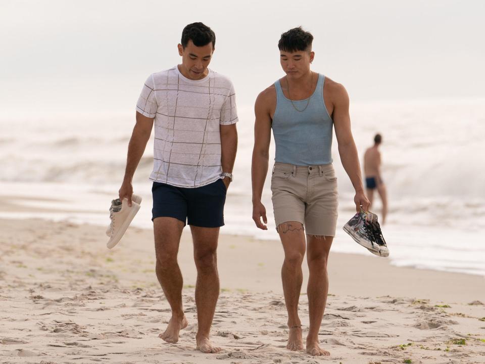 Conrad Ricamora and Joel Kim Booster walk on a beach in "Fire Island"