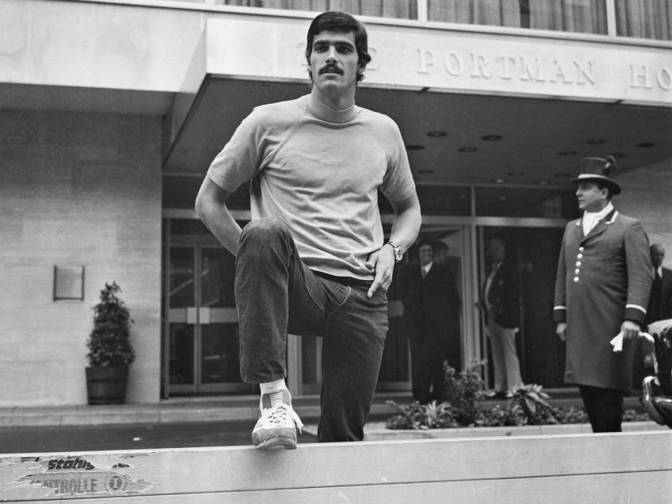 Mark Spitz in sweatsuit with leg up on bar in 1972