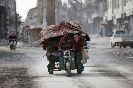 People drive a vehicle through a damaged neighbourhood in the northern Syrian town of al-Bab, Syria March 4, 2017. REUTERS/Khalil Ashawi