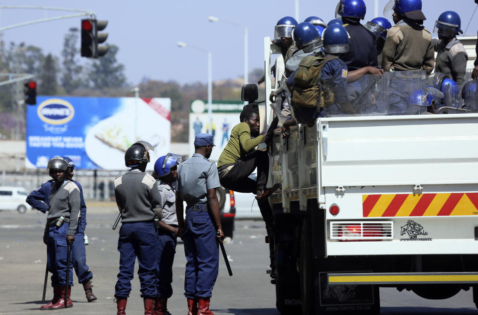 Riot police round up demonstrators during protests in Harare, Friday, Aug, 16, 2019. Zimbabwe's police patrolled the streets of Harare Friday morning while many residents stayed home and shops were shut fearing violence from an anti-government demonstration. Zimbabwe's High Court has upheld the police ban on the opposition protest.(AP Photo/Tsvangirayi Mukwazhi)