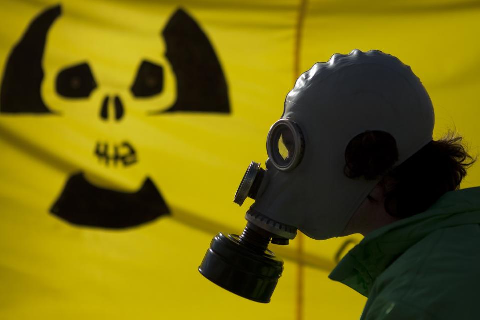 FILE - A man with a gas mask protests near the chancellery against nuclear power in the wake of Japan's Fukushima reactor disaster in Berlin, March 26, 2011. The country's three remaining reactors are being shut down, because Germany long ago decided to end nuclear power due to its potential for catastrophic meltdown and long-term radioactive legacy while simultaneously phasing out fossil fuels over climate change.(AP Photo/Markus Schreiber, File)