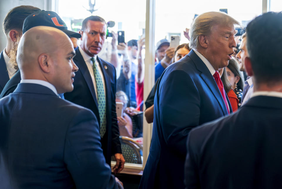 Former President Donald Trump's valet Walt Nauta, left, watches as Trump greets supporters at Versailles restaurant with Trump on Tuesday, June 13, 2023, in Miami. Nauta, a personal aide whom prosecutors say moved boxes from a storage room to Trump's residence for him to review and later lied to investigators about the movement, joined Trump on Tuesday in federal court. (AP Photo/Alex Brandon)