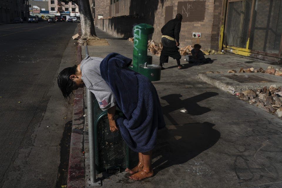 A mentally ill homeless woman leans on a rail after wetting her hair at a drinking fountain in the Skid Row area of Los Angeles, Monday, May 23, 2022. A controversial bill signed by Gov. Gavin Newsom could improve that by forcing people suffering from severe mental illness into treatment. But they need to be diagnosed with a certain disorder such as schizophrenia and addiction alone doesn't qualify. (AP Photo/Jae C. Hong)