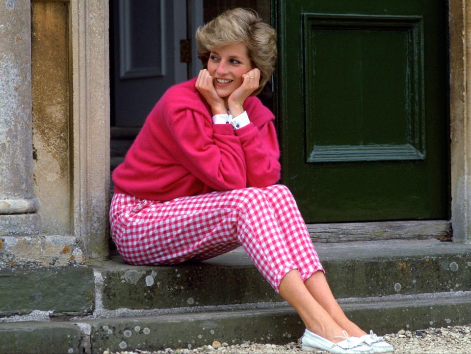 Princess Diana pictured outside her countryside home, Highgrove, in 1986. One of her most iconic looks, Diana chose a pair of high-waisted gingham pink trousers and an oversized fuchsia jumper with a white shirt underneath. The look was recreated in series four of The Crown. (Tim Graham Photo Library via Getty Images)