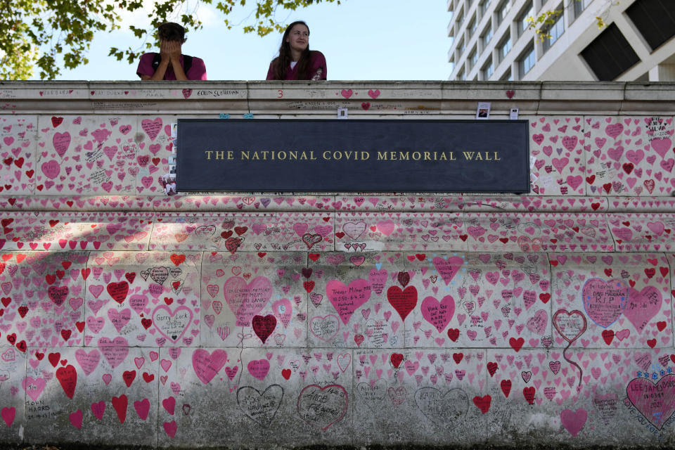 FILE - In this XXX, file photo, nurses from the nearby hospital rest atop the National Covid Memory Wall in London. Britain's Conservative government is hoping a combination of relatively high vaccination rates and common-sense behavior will keep a lid on coronavirus infections this fall and winter and avoid the need for restrictive measures. That plan employs a lighter touch than most nations. (AP Photo/Frank Augstein, File)