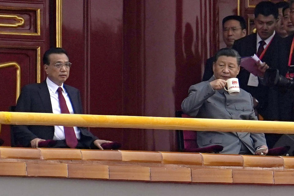 Chinese President Xi Jinping, right, drinks from an anniversary mug as he looks over towards Chinese Premier Li Keqiang during a ceremony to mark the 100th anniversary of the founding of the ruling Chinese Communist Party at Tiananmen Gate in Beijing Thursday, July 1, 2021. (AP Photo/Ng Han Guan)