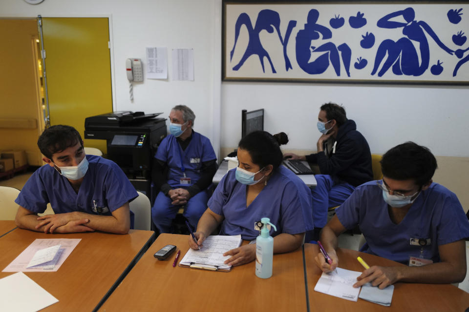 Medical staff, including Dr. Philippe Montravers, second left, attend a morning meeting, at Bichat Hospital, AP-HP, in Paris Tuesday, Dec. 1, 2020. One of the biggest hospitals in Paris, Bichat Hospital, this month reopened all 22 of its operating rooms. It is once again performing surgeries that were stopped during virus surges that pushed France's death toll past 55,000. (AP Photo/Francois Mori)