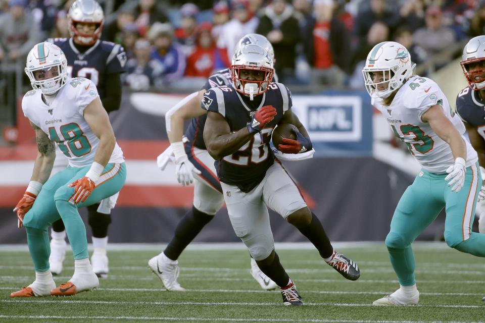 New England Patriots running back Sony Michel, center, runs from Miami Dolphins linebackers Calvin Munson, left, and Andrew Van Ginkel, right, in the first half of an NFL football game, Sunday, Dec. 29, 2019, in Foxborough, Mass. (AP Photo/Elise Amendola)