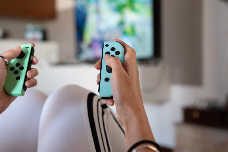 A person's hands playing with Nintendo Switch controllers