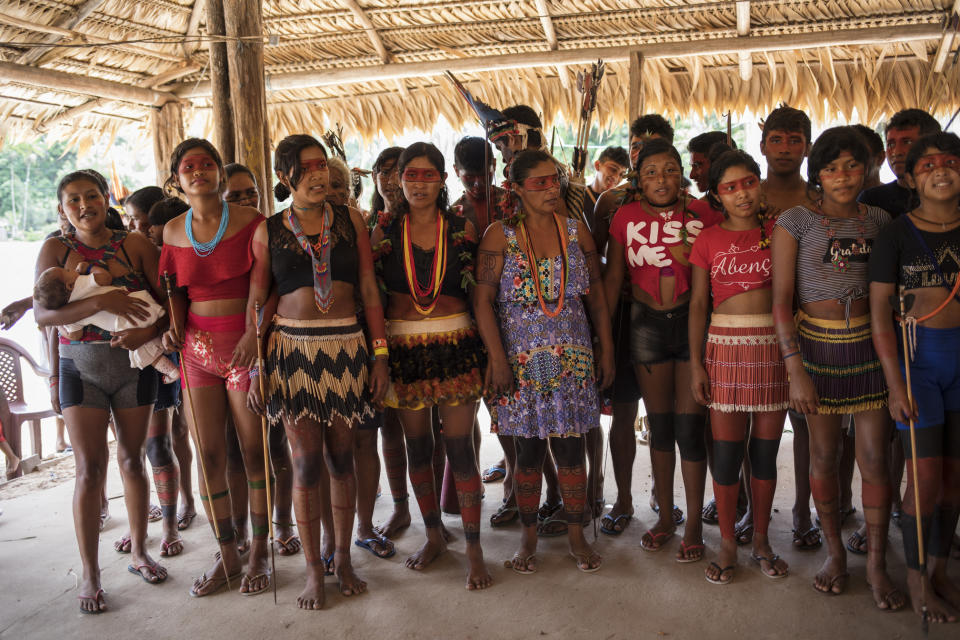 In this Sept. 3, 2019 photo, women prepare to perform a ritual dance during a meeting of Tembé tribes in a communal straw hut at the Tekohaw indigenous reserve, Para state, Brazil. Some had travelled long distances on dirt roads that cut through the lush jungle, or in boats along a muddy brown tributary of the Amazon River. (AP Photo/Rodrigo Abd)