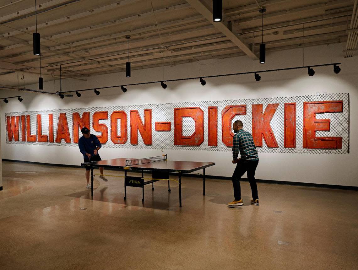 Dickies associates take a small work break in front of the original Williamson-Dickie sign at Dickies offices in downtown Fort Worth Texas, Thursday Mar. 28, 2024. The 102 year old work apparel company recently relocated to downtown Fort Worth. (Special to the Star-Telegram Bob Booth) Bob Booth/Special to the Star-Telegram Bob Booth