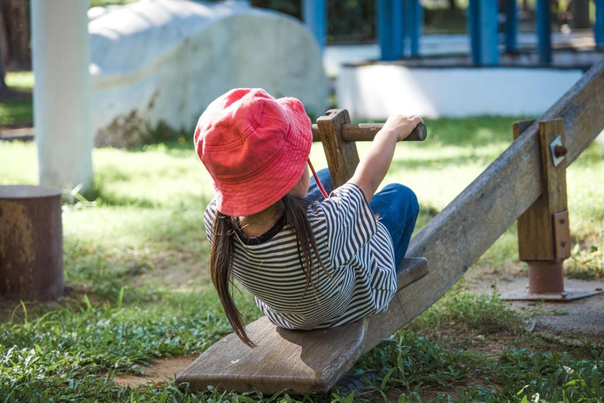 Girl Playing On Seesaw At Park