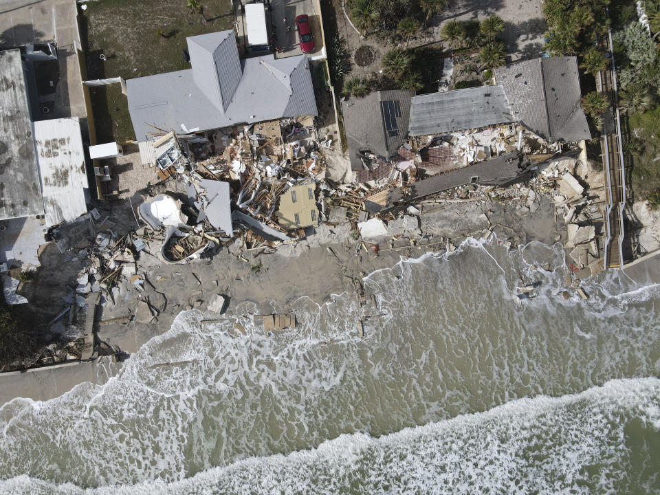 Waves lap the eroded beach below the half-collapsed homes of Nina Lavigna, at left, and her neighbor, after Hurricane Nicole swept away sand from the beach and from under foundations, Saturday, Nov. 12, 2022, in Wilbur-By-The-Sea, Fla. (AP Photo/Rebecca Blackwell)