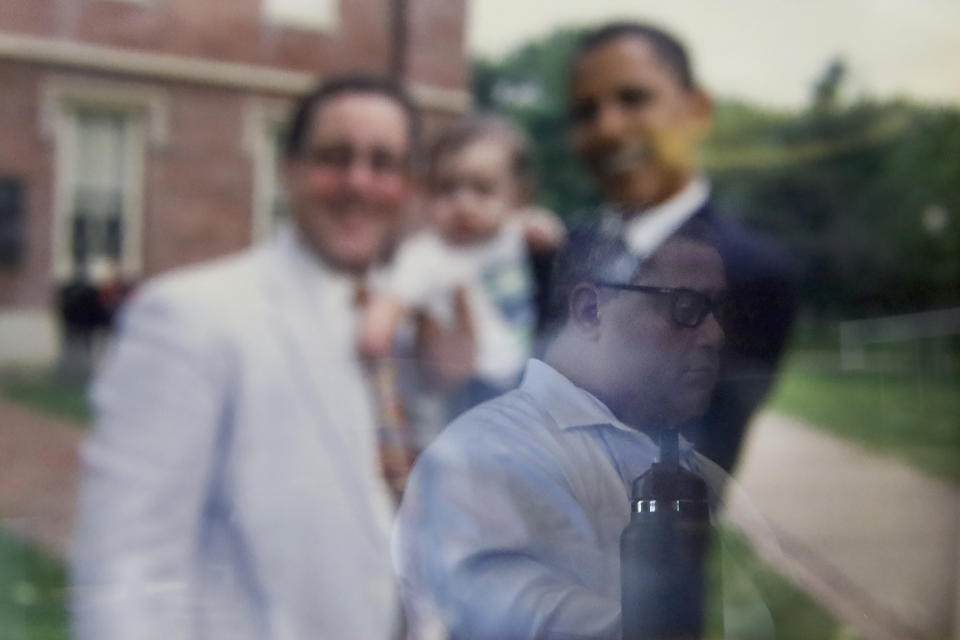 Knox County State's Attorney Jeremy Karlin is reflected on a framed photograph of him, his daughter and then, U.S. Senator Barack Obama, Tuesday, June 15, 2021, in his county courthouse office, in Galesburg, Ill. By early February, Karlin, a Democrat elected in November, was juggling four Galesburg shootings, three of them deadly and in April, he added another non-fatal shooting. "Here, it's meth. Meth touches half the cases I have. And it's not the meth you make in your house. It's the meth that comes across the border in 90-to-100-percent-pure form," Karlin, 52, said. (AP Photo/Shafkat Anowar)