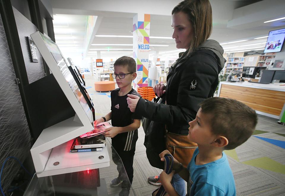 Ward Bravo, 9, from Ames, checks out books with his mother Amy and brother Lincoln, 6, in a self-check machine at Ames Piblic Library on Thursday, Feb. 2, 2024, in, 2024, in Ames, Iowa.