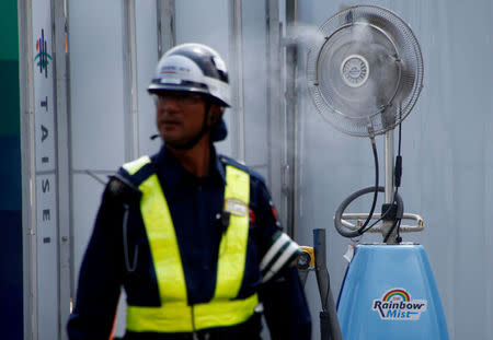 A worker stands in front of a fan spraying mist at the construction site of the New National Stadium, the main stadium of the Tokyo 2020 Olympics and Paralympic in Tokyo, Japan July 24, 2018. REUTERS/Kim Kyung-Hoon