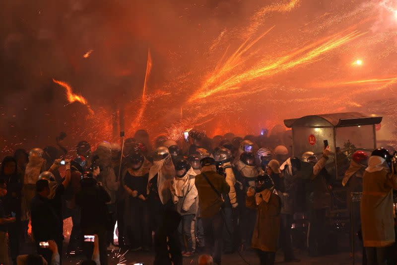 Participants wearing motorcycle helmets get sprayed with firecrackers, during the 'Beehive Firecrackers' festival at the Yanshui district in Tainan