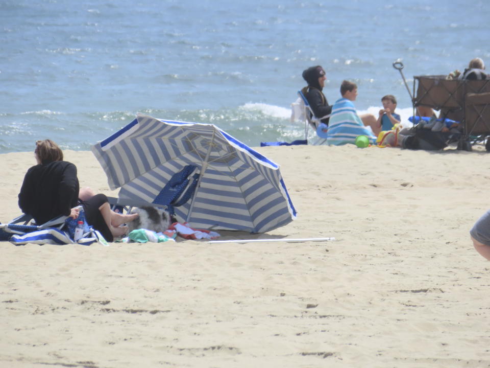 People sit on the beach on a weekday afternoon in Ocean Grove, N.J. on May 2, 2024.The state of New Jersey says the Ocean Grove Camp Meeting Association is violating state beach access laws by keeping people off the beach until noon on Sundays. (AP Photo/Wayne Parry)