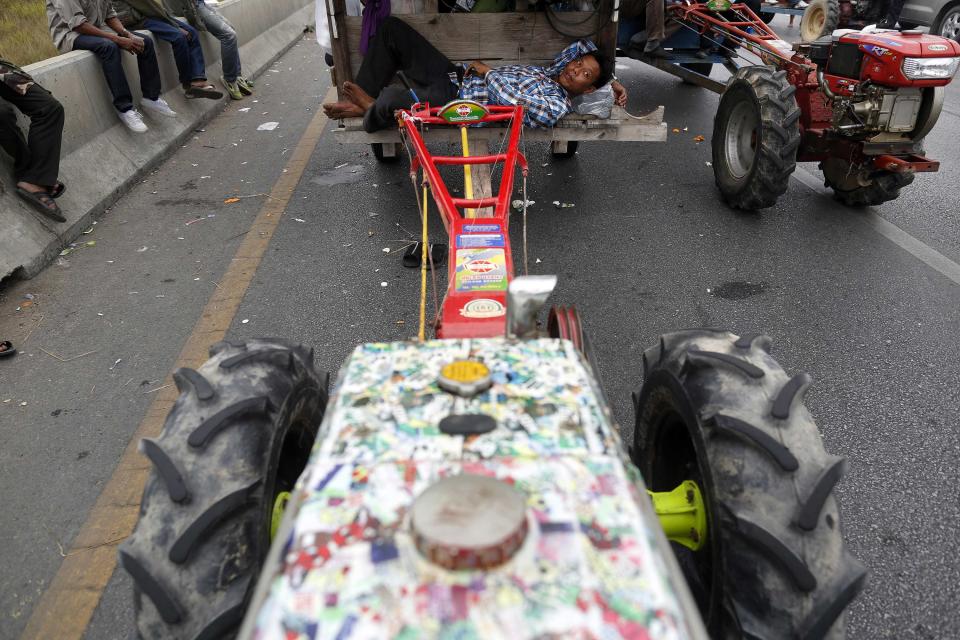 Rice farmers rest by their tractors on a main highway where they spent a night in Ayutthaya province February 21, 2014. Thai farmers called off a tractor drive to Bangkok's main airport to protest against not being paid under a rice subsidy scheme after an assurance they would get their money, a spokesman said, welcome news for Prime Minister Yingluck Shinawatra. REUTERS/Damir Sagolj (THAILAND - Tags: SOCIETY CIVIL UNREST POLITICS AGRICULTURE)