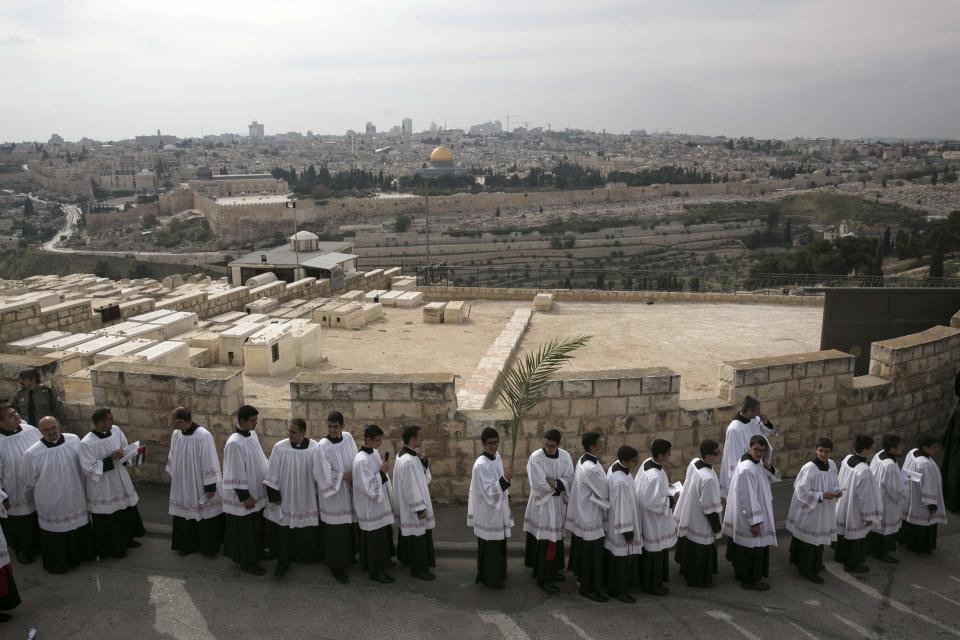 A member of the Catholic clergy holds a palm frond during a Palm Sunday procession on the Mount of Olives in Jerusalem