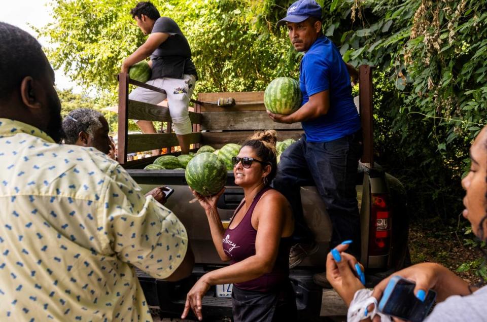 “The Watermelon Lady,” Sanjuana Sanchez, hands out fresh yellow watermelon from the back of a pickup truck on New Bern Avenue in Raleigh on Thursday, June 20, 2024. Sanchez saw an uptick in watermelon and fresh fruit sales Thursday as the Triangle experienced a heat wave.