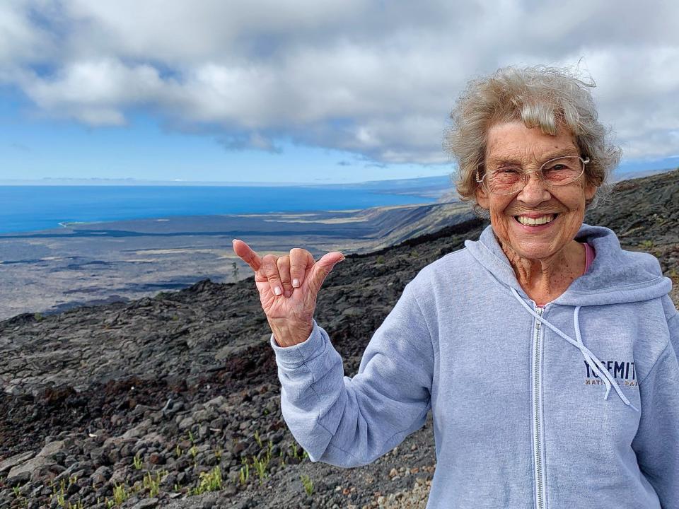 Grandma Joy smiles in Hawaiʻi Volcanoes National Park and gives a Shaka sign, which loosely means, "Right on."