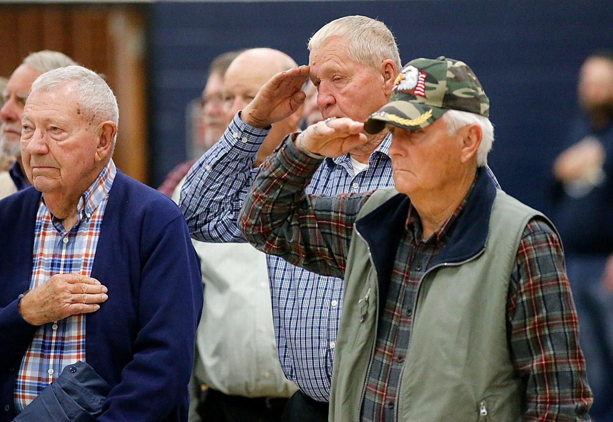 Veteran Dick Dilgard, right, salutes during the signing of the National Anthem at Hillsdale Local Schools Veterans Day program at the high school gym on Friday, Nov. 11, 2022. TOM E. PUSKAR/ASHLAND TIMES-GAZETTE