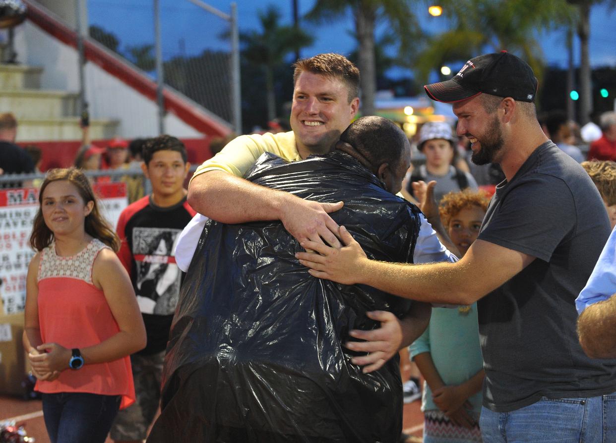 Surrounded by friends, Former Vero Beach High School football player Bryan Stork, (center) shares a hug with coach Teddy Floyd before having his former high school jersey number retired during half-time at the Citrus Bowl May, 15, 2015. Stork is the center for the New England Patriots.