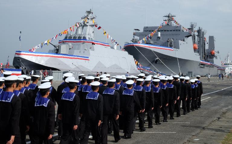 Navy soldiers walk past a 500-tonne corvette (L) named 'Tuo Chiang' -- 'Tuo River' -- is the first of its kind ever produced by Taiwan as "the fastest and most powerful" in Asia at the Tsoying navy base in southern Kaohsiung on March 31, 2015