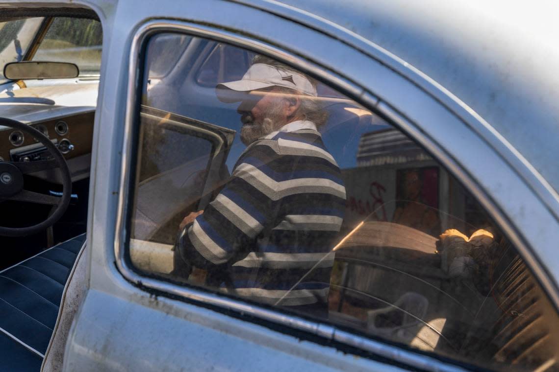 “Crazy Dale” Varnam is reflected in the window of one of this vintage Volkswagens on Thursday, February 22, 2024 in Varnamtown, N.C. Varnam has collected all types of vehicles, which are housed on 20 acres of his property. Robert Willett/rwillett@newsobserver.com