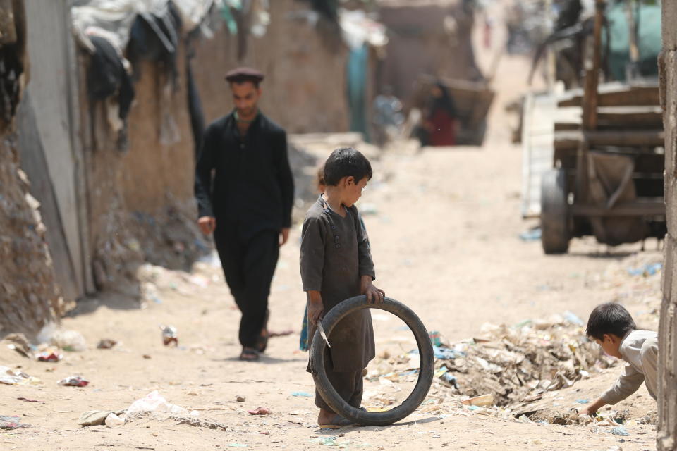 Children play with a bicycle wheel as Afghan refugees are struggling to survive under difficult conditions in Islamabad, Pakistan on May 29, 2022. Refugees living in the camp continue to stay in the country due to the economic and political problems in Afghanistan. / Credit: Muhammed Semih Ugurlu/Anadolu Agency via Getty Images