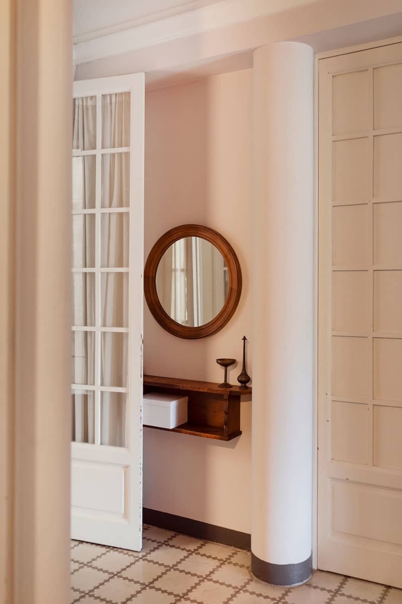 Round mirror hung in neutral toned hallway.