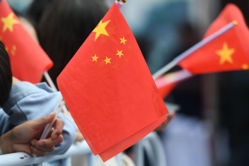 Pictured are people holding small China flags. 