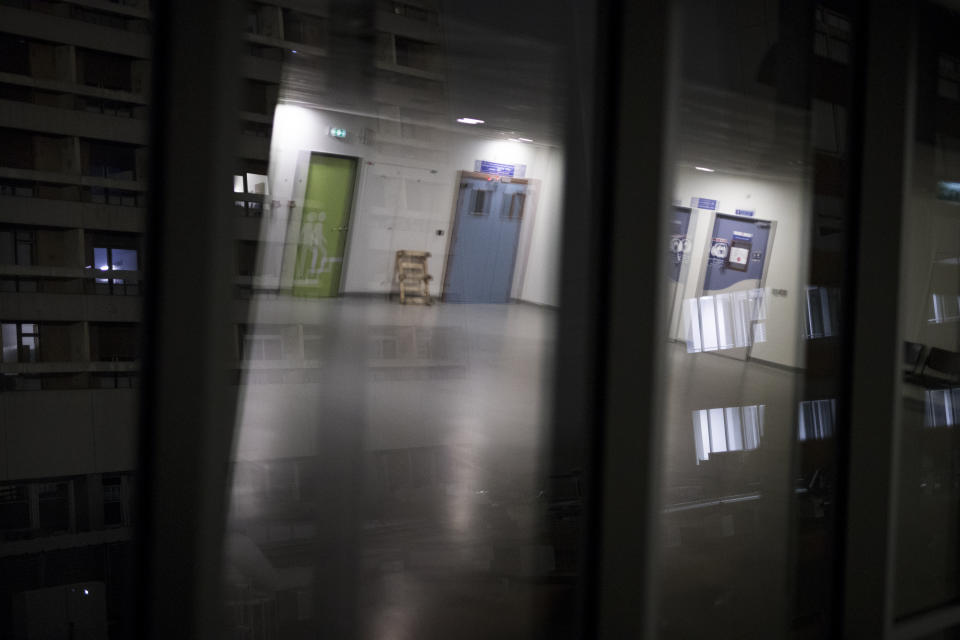 Illuminated hospital rooms are can be seen through the reflection of a vacant corridor during the night shift at the La Timone hospital in Marseille, southern France, Friday, Nov. 13, 2020. In Marseille the second wave of the coronavirus is bringing even more people to the ICU than the first one in the spring, many in more severe condition. (AP Photo/Daniel Cole)