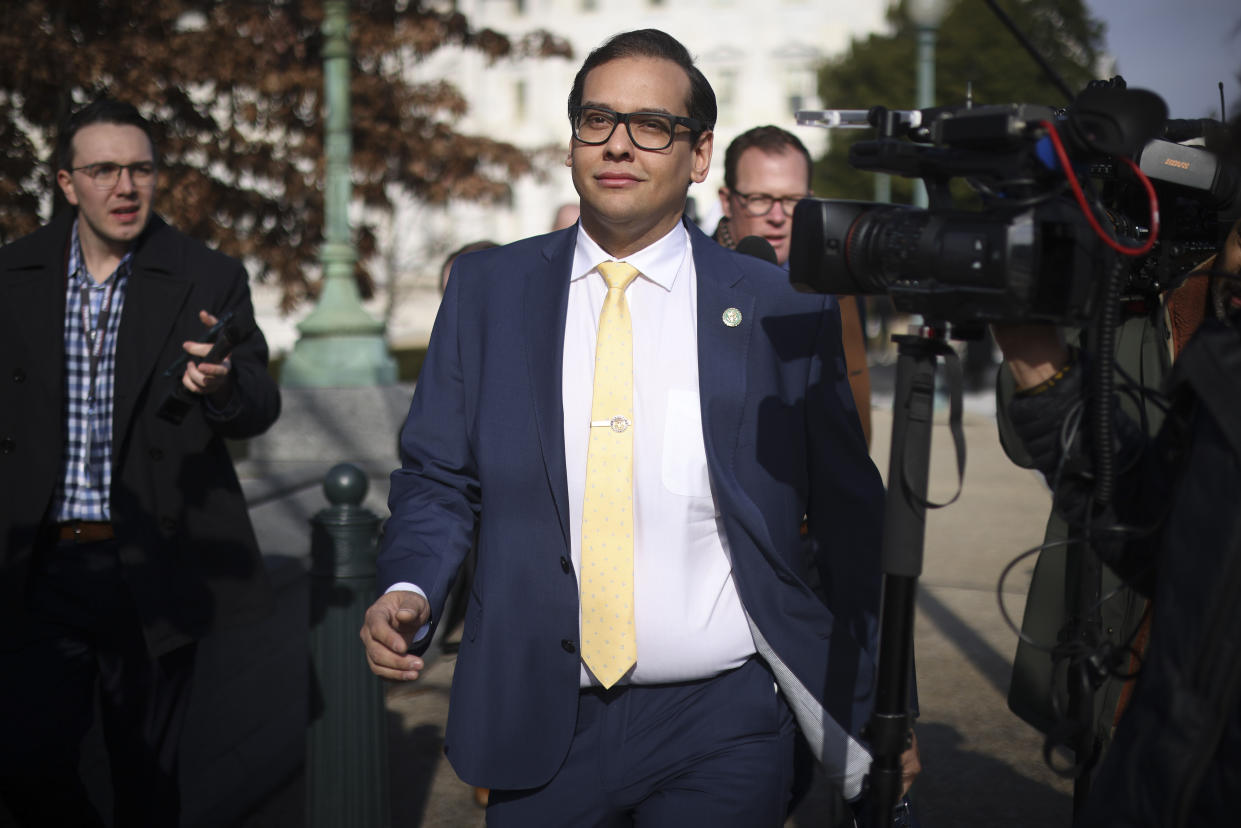 Rep. George Santos, looking upbeat, outside the U.S. Capitol, surrounded by reporters.