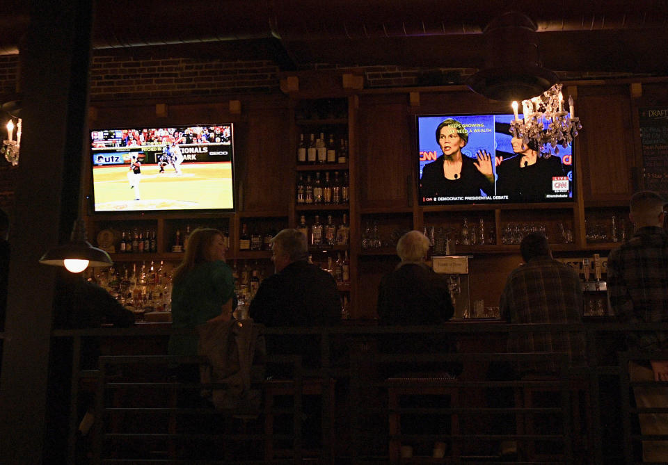 Patrons at the Hawk 'n' Dove sit in front of television screens televising Game 4 of the NLCS between Washington Nationals and the St. Louis Cardinals and a debate by Democratic presidential candidates, Tuesday, Oct. 15, 2019, in Washington. Tuesday night presents a quandary for many Washingtonians: the Democratic presidential debate on a night when the Washington Nationals have a chance to make it to their first-ever World Series. (AP Photo/Nick Wass)