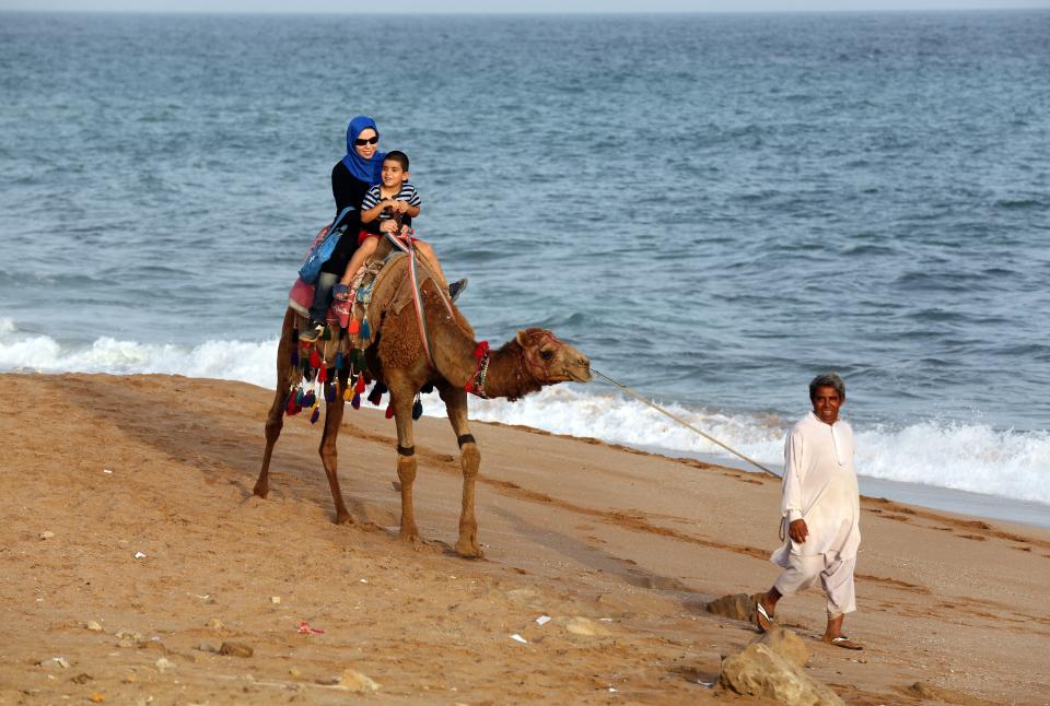 A woman and child ride a camel along the Gulf of Oman coast in Chabahar, Iran, on May 12, 2015.