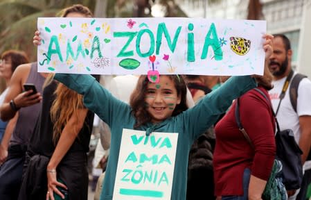 A girl holds a sign ahead of the demonstration to demand more protection for the Amazon rainforest in Rio de Janeiro