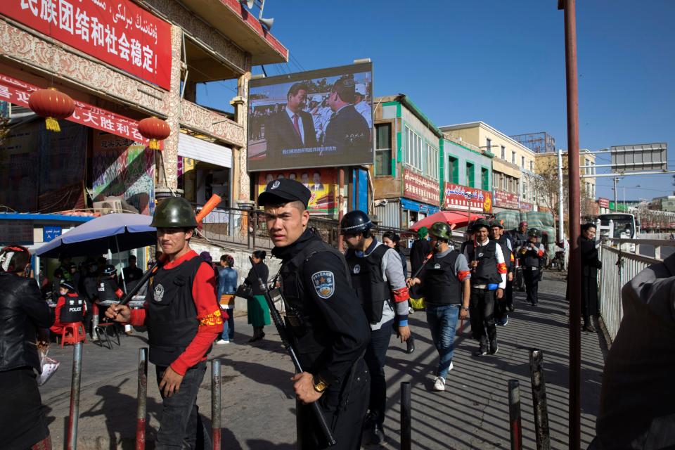Armed civilians patrol the area outside the Hotan Bazaar where a screen shows Chinese President Xi Jinping in Hotan in western China's Xinjiang region, Nov. 3, 2017. China's discriminatory detention of Uyghurs and other mostly Muslim ethnic groups in the western region of Xinjiang may constitute crimes against humanity, the U.N. human rights office said in a long-awaited report Wednesday, Aug. 31, 2022, which cited "serious" rights violations and patterns of torture in recent years.