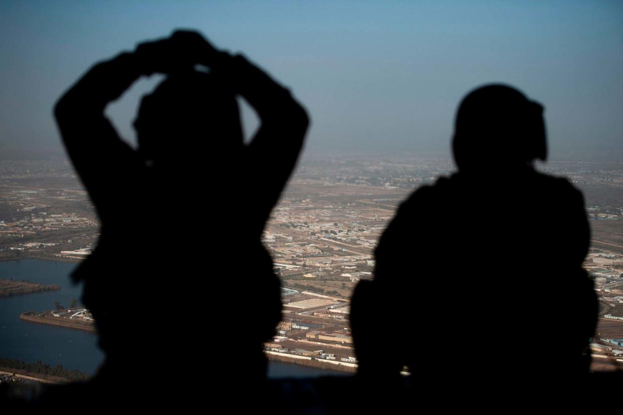 In this file photo US Army helicopter crew members look out of their helicopter as they fly from the US Embassy to Baghdad International Airport: POOL/AFP via Getty Images