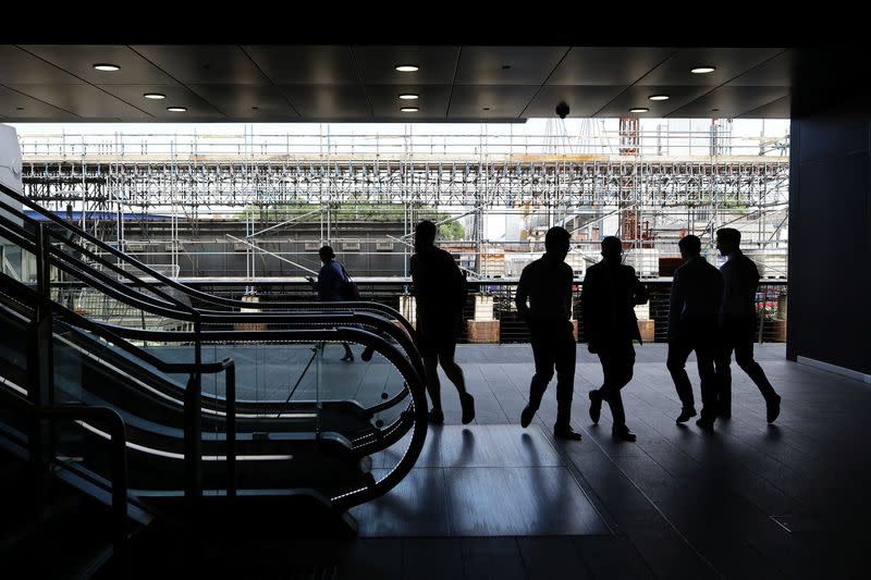 People walk past the Crossrail construction site in the financial district of Canary Wharf in London