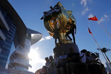 Pro-democracy activists climb the Golden Bauhinia sculpture during a protest to demand full democracy ahead of the 20th anniversary of the handover from Britain to China, in Hong Kong, China June 28, 2017. REUTERS/Tyrone Siu