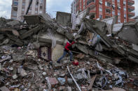 A man walks among rubble as he searches for people in a destroyed building in Adana, Turkey, Monday, Feb. 6, 2023. A powerful quake has knocked down multiple buildings in southeast Turkey and Syria and many casualties are feared. (AP Photo/Khalil Hamra)