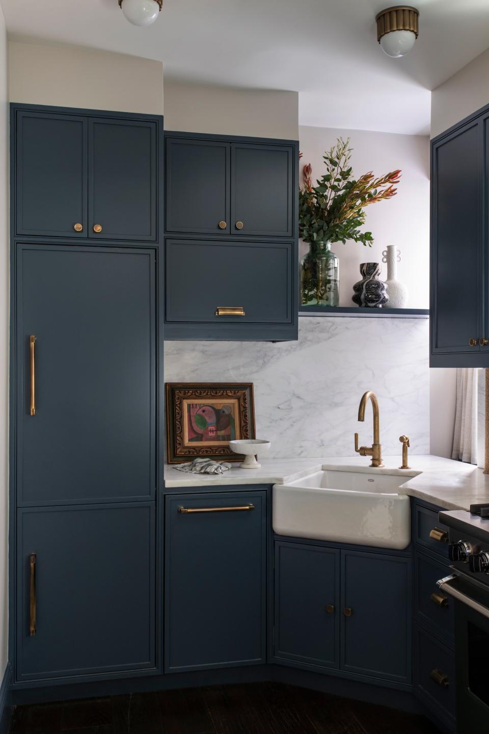 AFTER: Louise steeped the kitchen in calm and color by way of deep teal cabinets and a pristine marble backsplash. She added some shine with burnished knobs and pulls by Classic Brass. A Pedro Coronel painting sits on the counter.