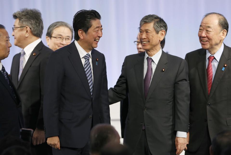 Japanese Prime Minister Shinzo Abe, center left, with lawmakers and members of his ruling Liberal Democratic (LDP) Party attend his party's annual convention at a hotel in Tokyo, Sunday, March 5, 2017. Japan's ruling party approved a change in party rules Sunday that could pave the way for Prime Minister Shinzo Abe to become the country's longest-serving leader in the post-World War II era. (AP Photo/Shizuo Kambayashi)