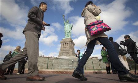 People walk past the Statue of Liberty on Liberty Island in New York, October 13, 2013. REUTERS/Carlo Allegri
