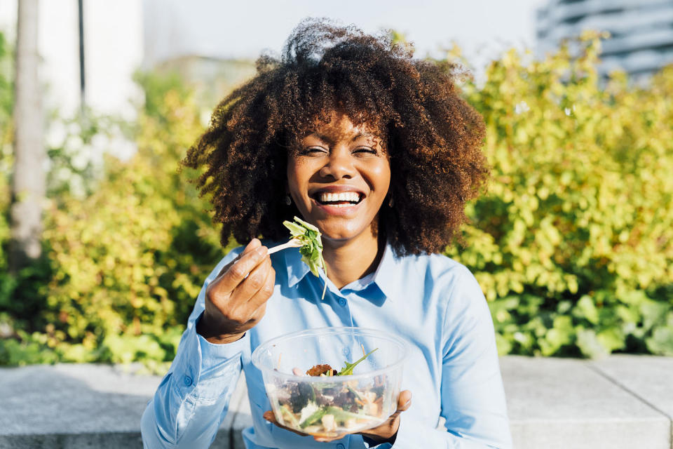 Happy businesswoman eating salad on sunny day (Westend61 / Getty Images stock)